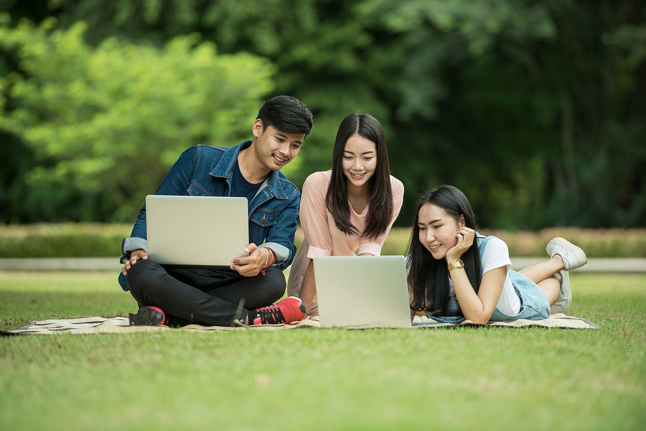 芝生でパソコンをする女学生